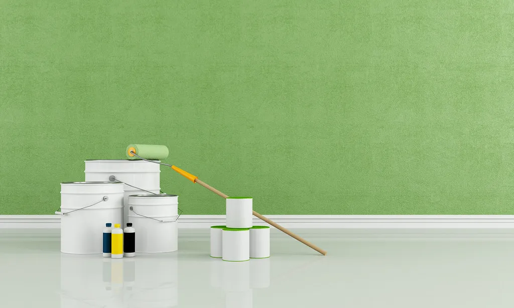 Mur fraîchement repeint, pots de peinture et rouleau au sol